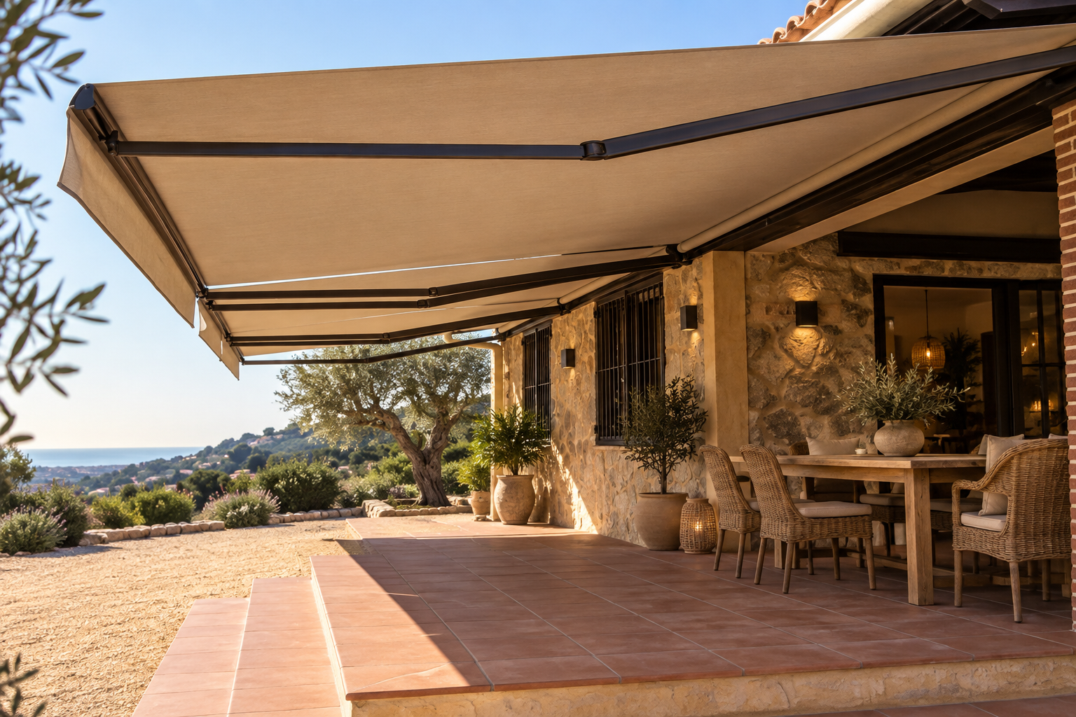 Dos toldos extensibles beige protegiendo una gran terraza de una casa de piedra