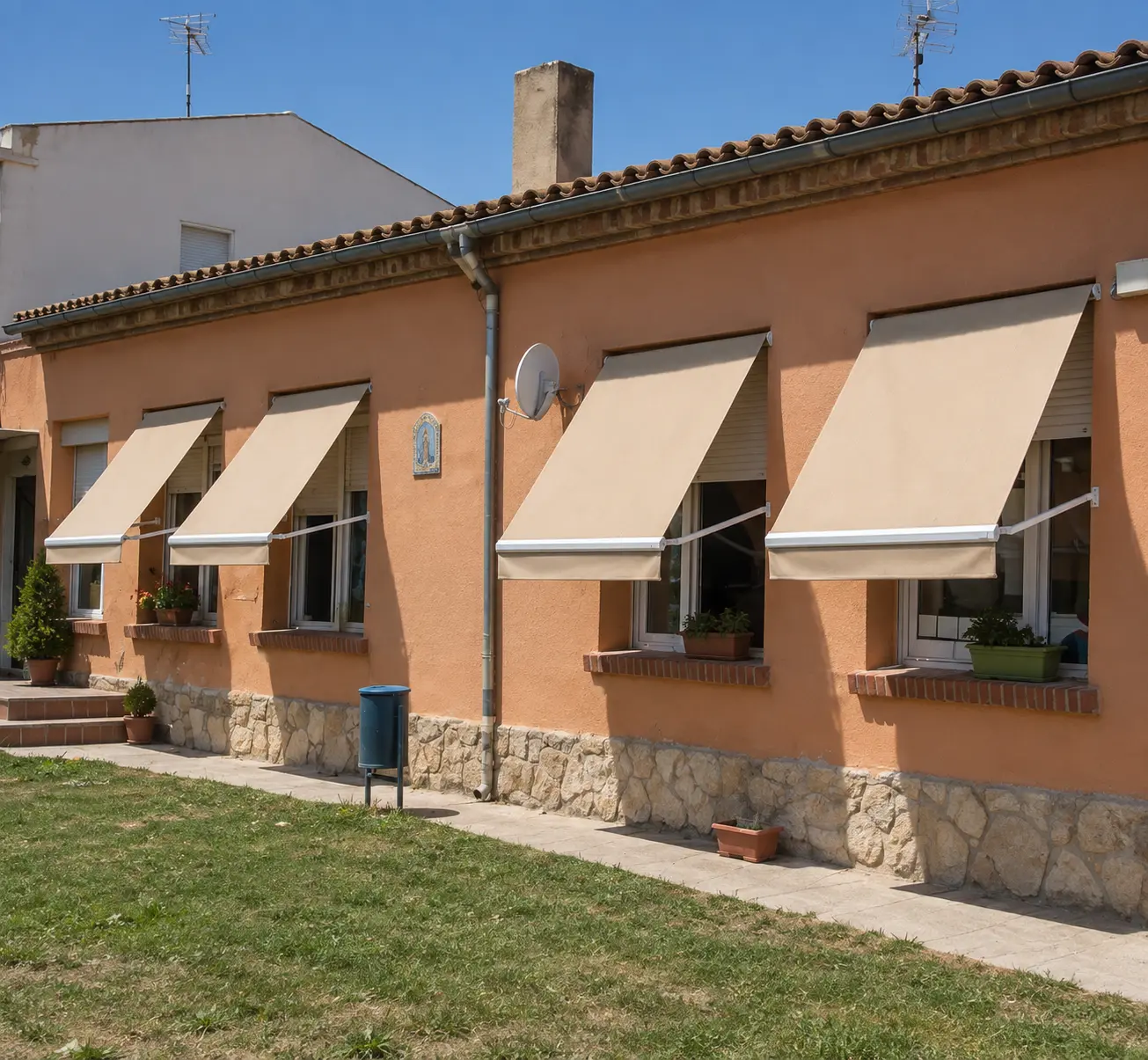 Cuatro toldos punto recto beige en fachada de vivienda con jardín