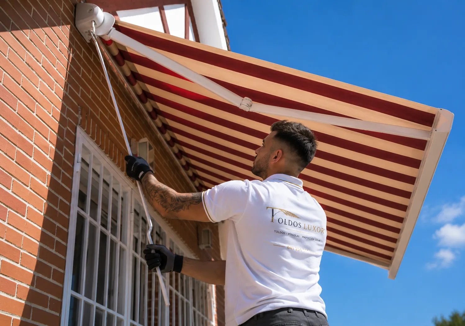 Instalador de Toldos Luxor montando un toldo de rayas en la fachada de una vivienda