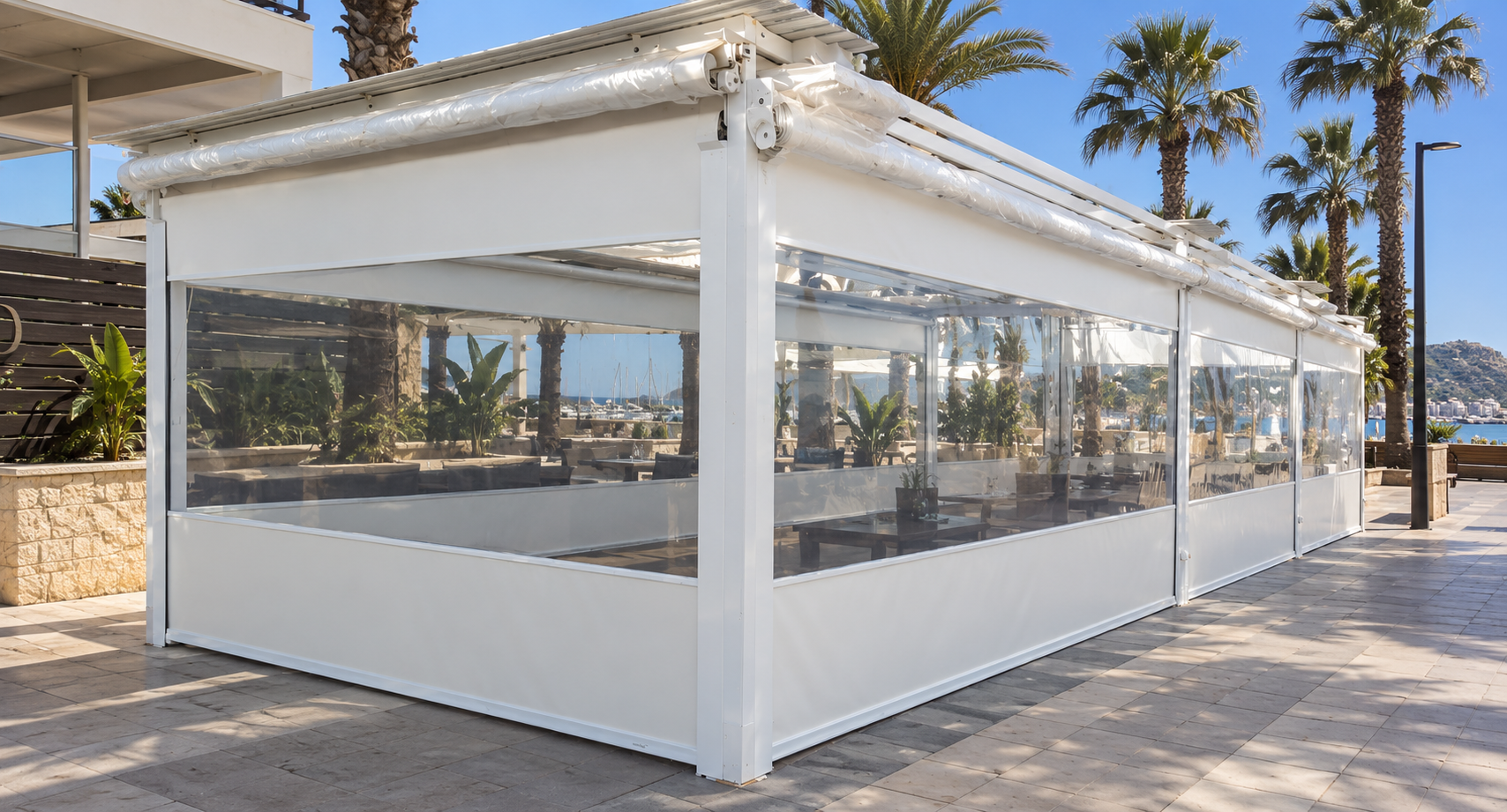 Cerramiento con toldos telón blancos y cristal en la terraza de un restaurante frente al puerto