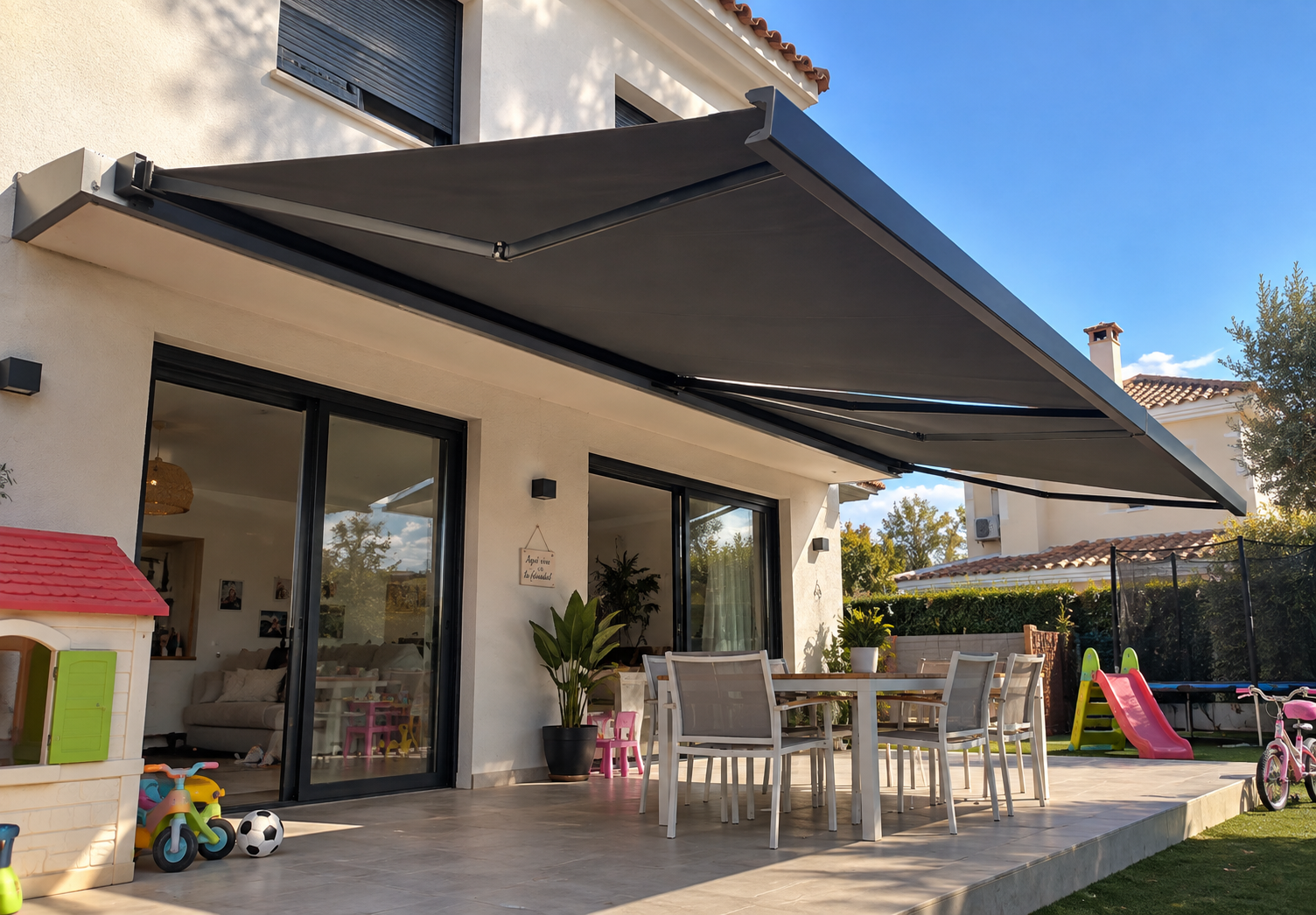 Toldo motorizado gris extendido sobre la terraza de una vivienda familiar